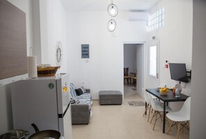 A modern kitchen with a refrigerator, a dining area with a table and chairs, and a small kitchenette. - Aimou Studio's & Apartment's (Piraeus)