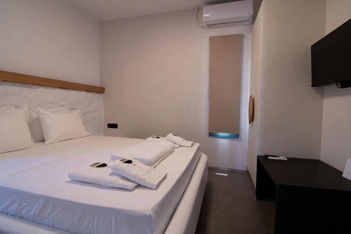 Ein Hotelzimmer mit einem Bett, einem Schreibtisch, einem Flachbildfernseher und einer Wand-Klimaanlage.