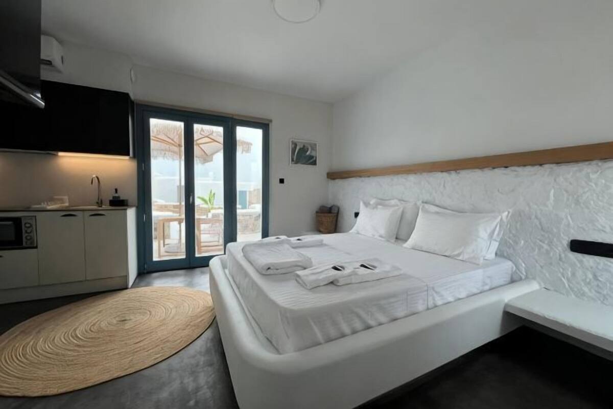 Ein Schlafzimmer mit Bett, Schreibtisch, Stuhl und Blick ins Freie.