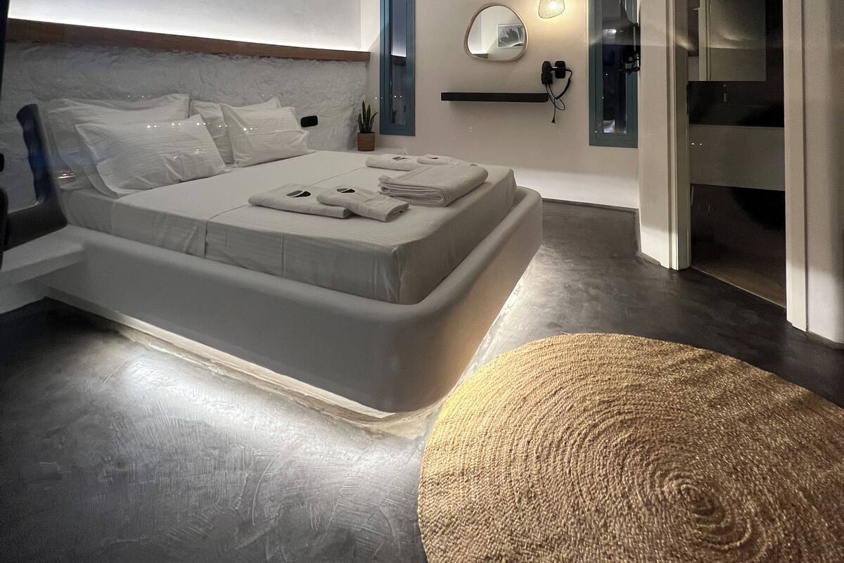Ein modernes Schlafzimmer mit einem großen Bett, Nachttischen, einem Spiegel und einer kleinen Pflanze.