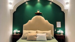 A bedroom with a green wall, a large bed with a beige headboard, two bedside tables with lamps, and a small shelf with a lamp. - Maison Ciccio - il Monticello with private Sauna (Campania)