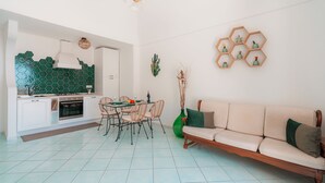 A modern kitchen with white cabinets, a hexagonal backsplash, and a dining area with a table and chairs. - Maison Ciccio - il Monticello with private Sauna (Campania)