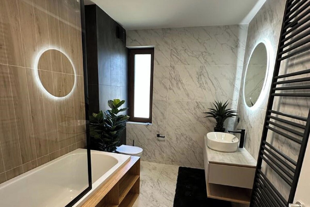 A modern bathroom with a freestanding bathtub, a vanity with a mirror, and a toilet.
