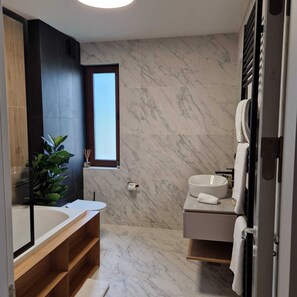 Un baño moderno con un espejo grande, un tocador de madera, una bañera y zona de ducha.