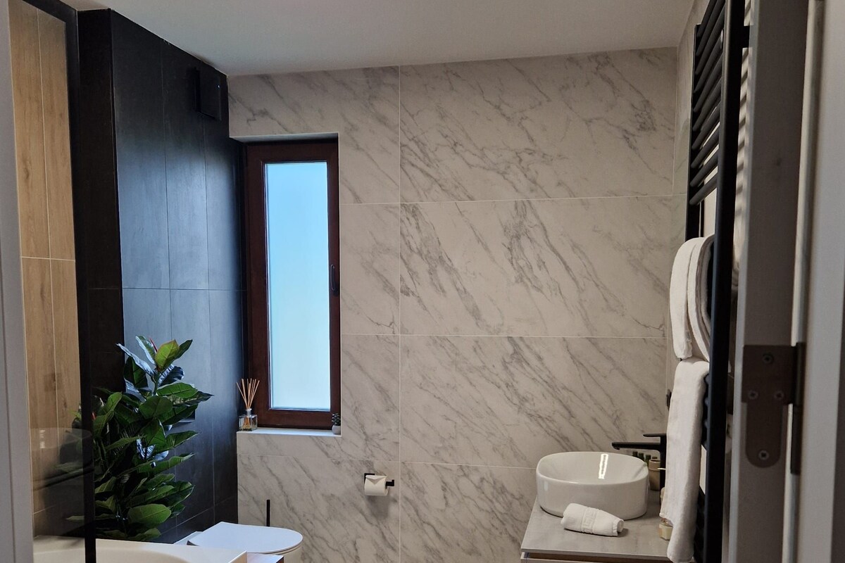 A modern bathroom with a large mirror, a wooden vanity, a bathtub, and a shower area.