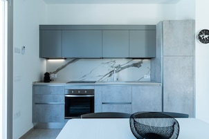 Una cocina moderna con gabinetes grises, salpicadero de mármol y horno empotrado.