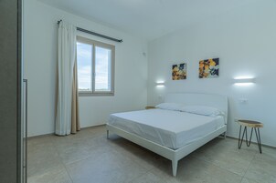 Un dormitorio con una cama, cortinas, un ventanal y dos obras de arte colgadas en la pared.