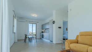 Een moderne woonkamer met een bank en een eethoek met stoelen en een tafel.