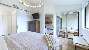 Ein modernes Schlafzimmer mit einem großen Bett, einem Schreibtisch und Blick auf einen Balkon.
