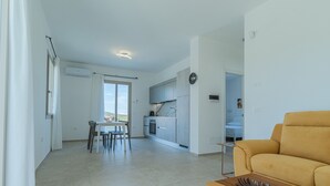 A modern apartment with a dining area, kitchen, and living room. - Appartamento La Perla by Wonderful Italy (Olbia)