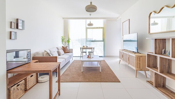 Ein modernes Wohnzimmer mit Sofa, Couchtisch, Fernseher und Essbereich.