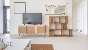 Ein modernes Wohnzimmer mit Flachbildfernseher, Holzschrank und Spiegel.