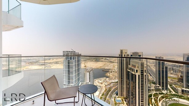 A high-rise balcony with a view of a cityscape, featuring modern buildings and a body of water. - Classy & Cozy 2BR Harbour Point (Dubai)