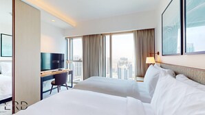 A hotel room with two beds, a desk with a TV, and a large window with a city view. - Classy & Cozy 2BR Harbour Point (Dubai)