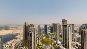 A high-rise residential building complex with multiple towers, a central circular park, and a body of water in the background. - Classy & Cozy 2BR Harbour Point (Dubai)