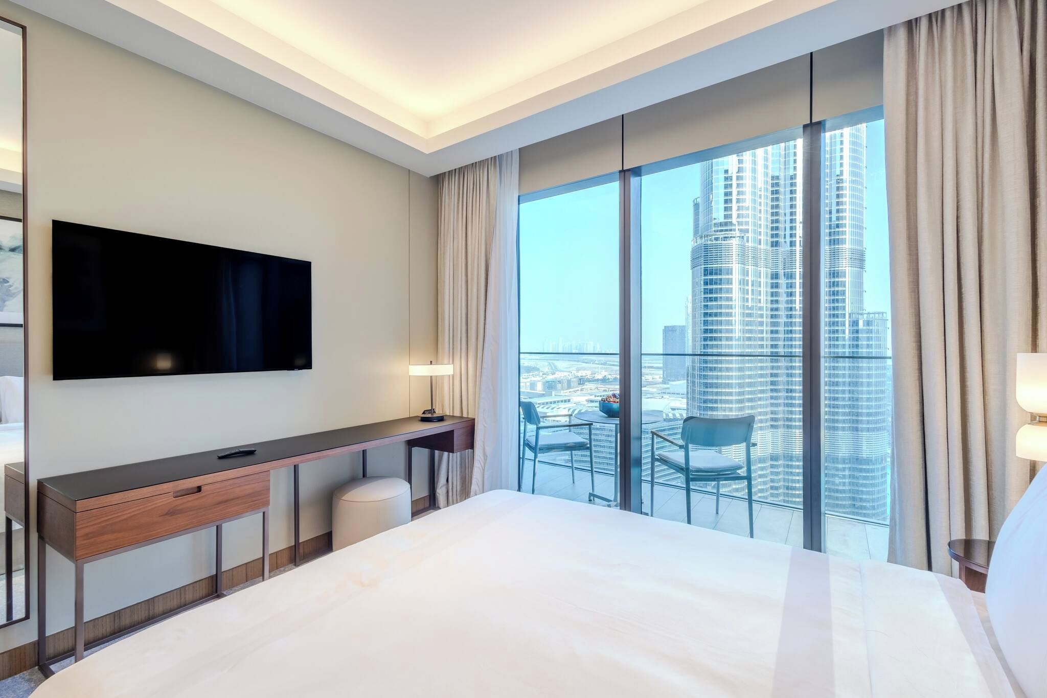 Hotelkamer met een groot bed, een bureau, een flatscreen televisie en een balkon met uitzicht over de stad.