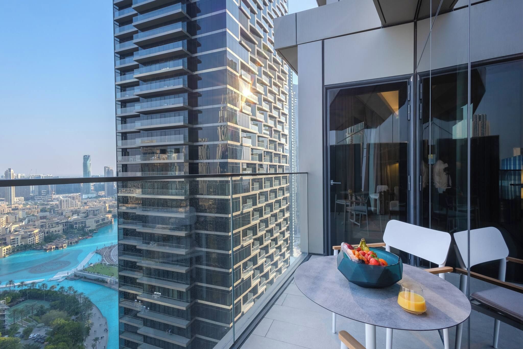 A balcony with a table, chairs, and a bowl of fruit.