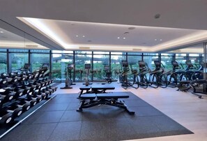 Et moderne fitnesscenter med træningsudstyr, store vinduer og udsigt til grønne områder.