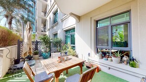 A patio with a wooden table and chairs, surrounded by potted plants and a small garden area.