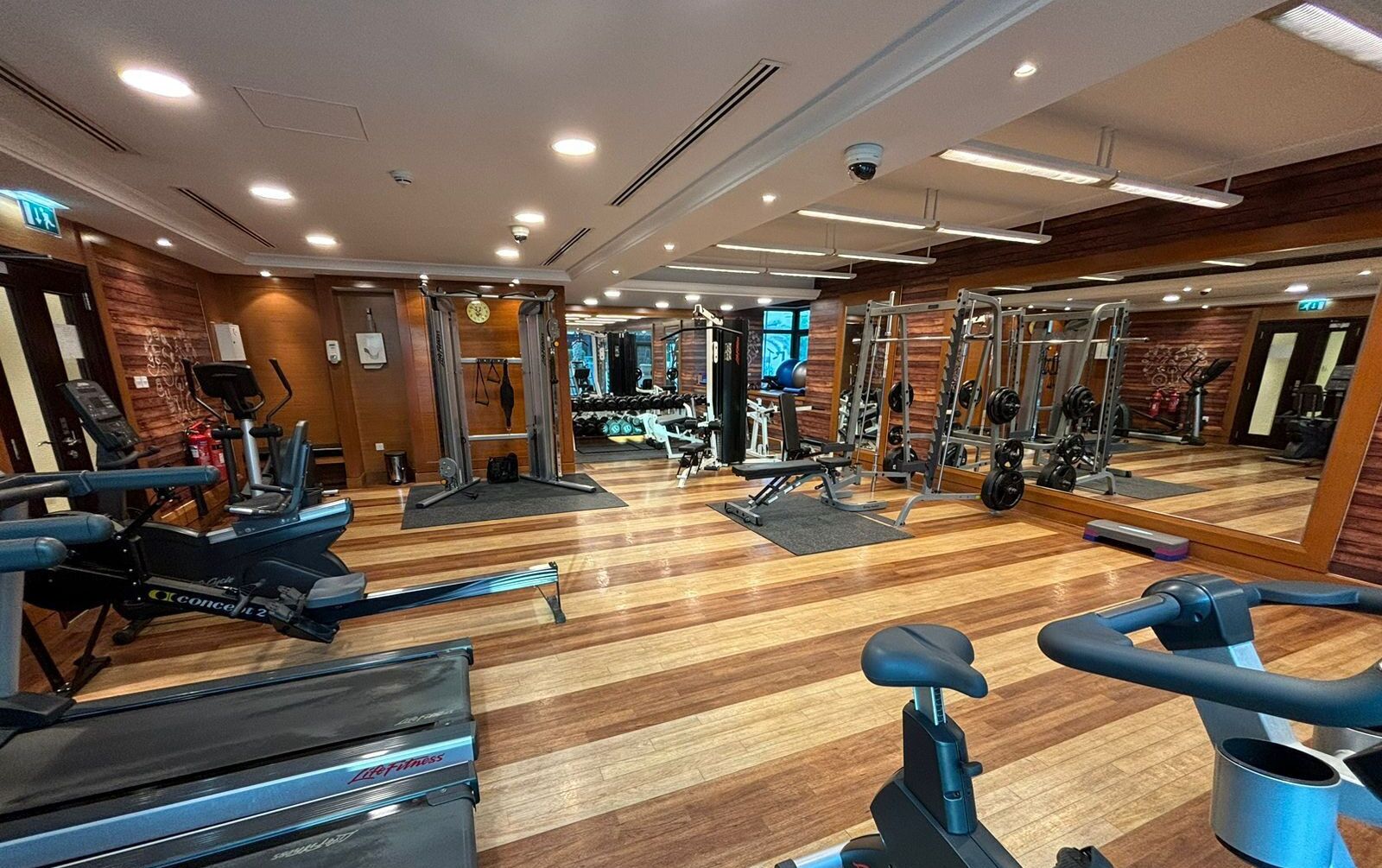 Una palestra con macchinari cardio, attrezzature per sollevamento pesi e parete con specchi.