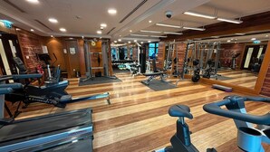 Un gimnasio con máquinas de cardio, equipo de levantamiento de pesas y un muro de espejos.