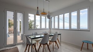 A modern dining area with a glass table, white chairs, and pendant lighting.