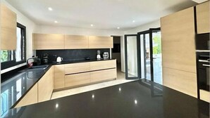 A modern kitchen with a black countertop, wooden cabinets, and a large island.