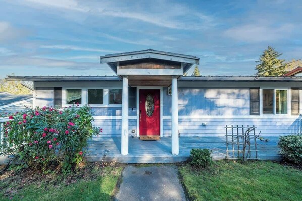 A two-story house with a red door and white columns, surrounded by a well-maintained garden. - Spacious 4b2b house / Partial lake views/ Backyard (Seattle)