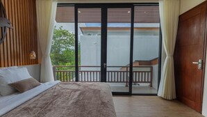 A bedroom with a large bed, a wooden headboard, a sliding glass door to a balcony, and a view of greenery outside. - Jobon Villas  (Ungasan)
