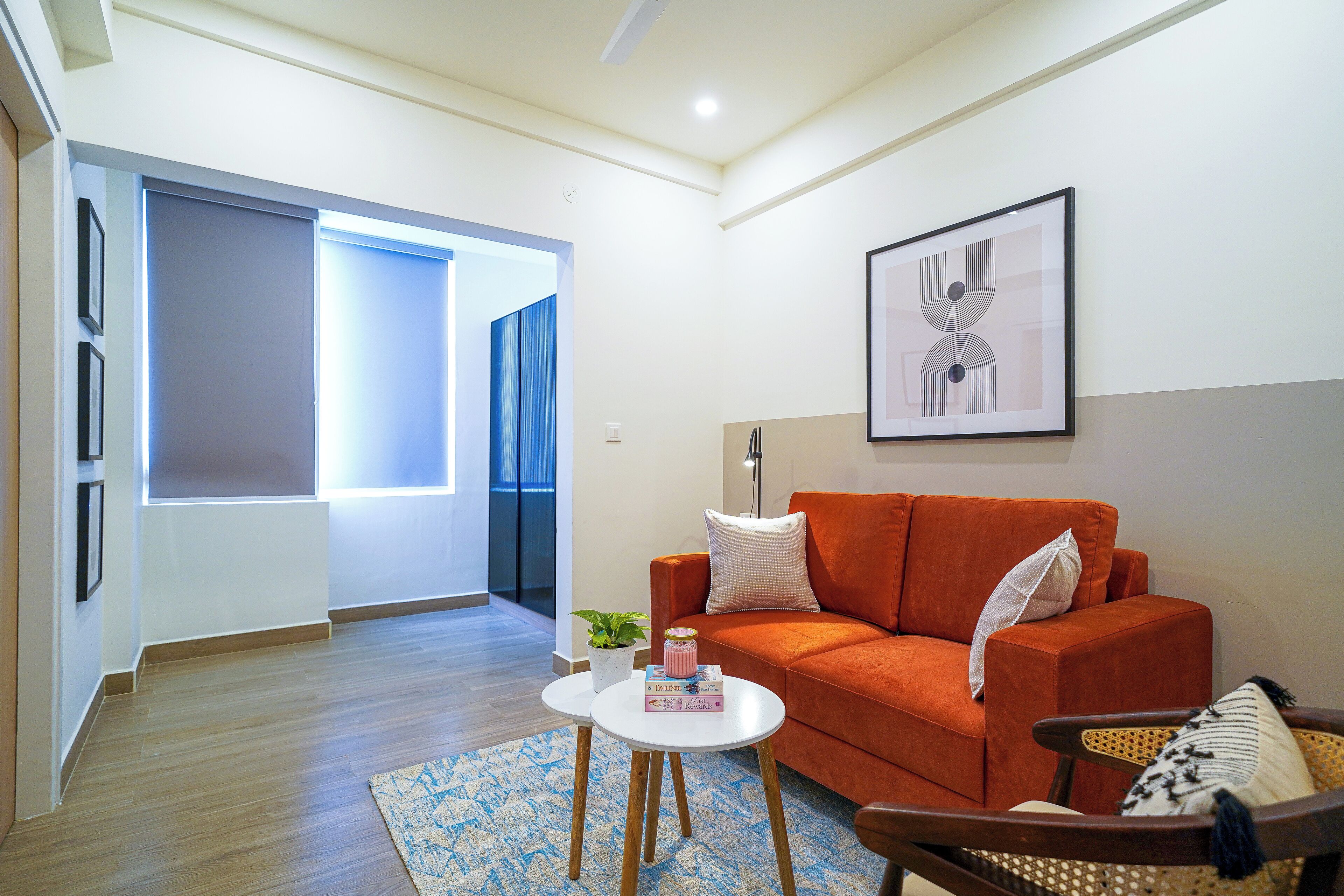 Un salon moderne avec un canapé, une table basse et un fauteuil. Un tableau encadré est accroché au mur et une plante en pot est posée sur la table basse.