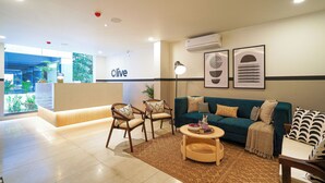 Um lobby moderno de hotel com balcão de recepção, área de estar e obras de arte nas paredes.