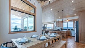 Een moderne keuken met houten kastjes, een eethoek met een groot raam en uitzicht op de omgeving.