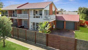 A two-story house with a balcony, a fenced yard, and a red roof. - Sandy Bliss - Walk to the beach (Torquay)