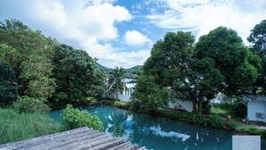 A serene riverside view with lush greenery and a calm river, reflecting the sky. - Navagio Boutique Koh Chang (Ko Chang)