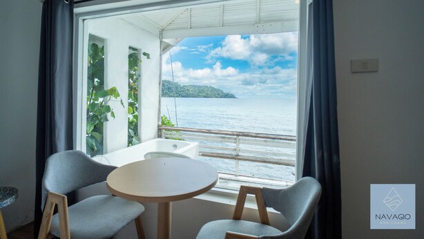A room with a view of the sea, a round table, two chairs, and a small white table. - Navagio Boutique Koh Chang (Ko Chang)