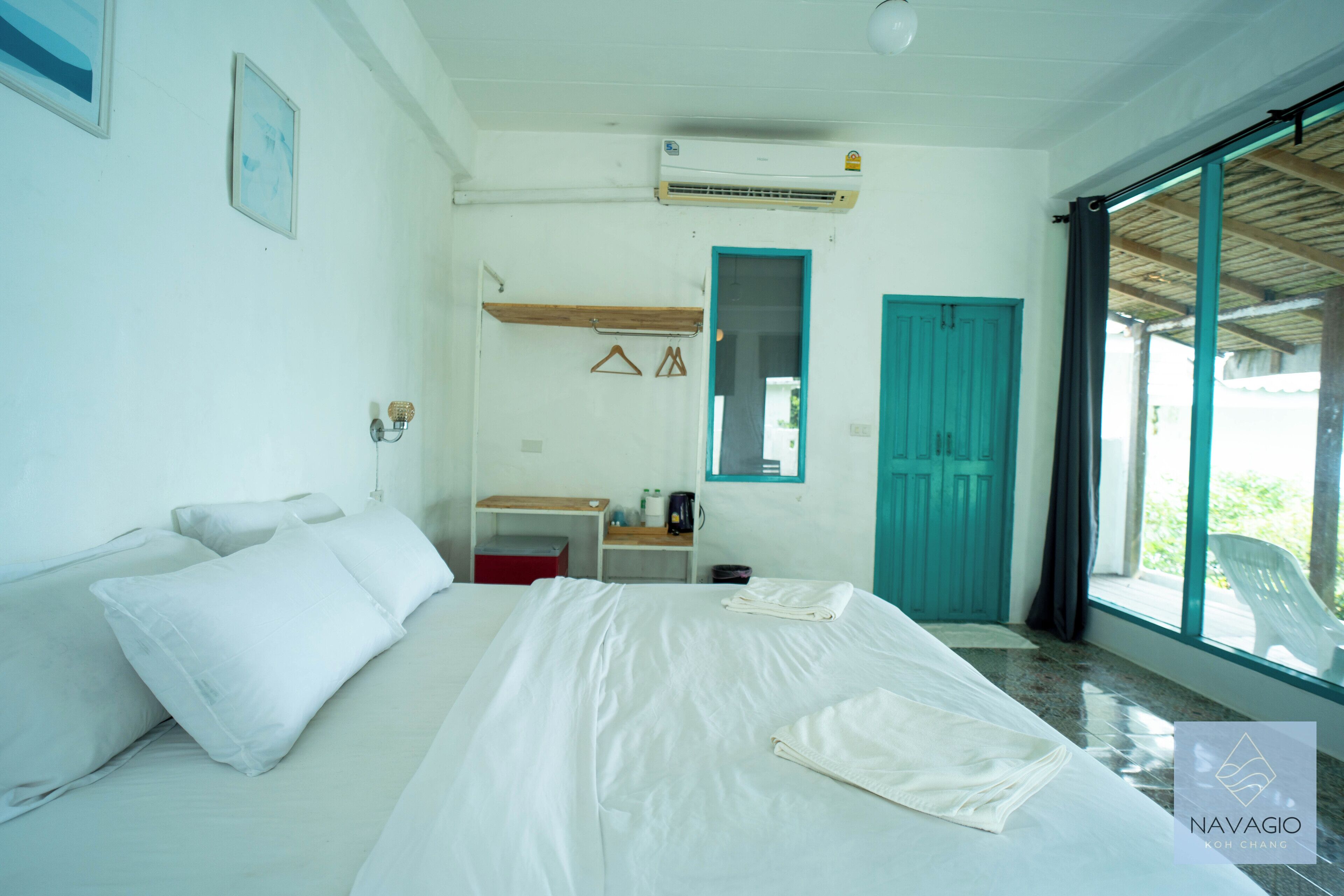 A hotel room with a bed, a desk, a chair, and a window.