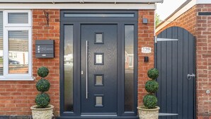 Una casa moderna de dos pisos con puerta principal color gris oscuro, fachada de ladrillo y entrada con portón.