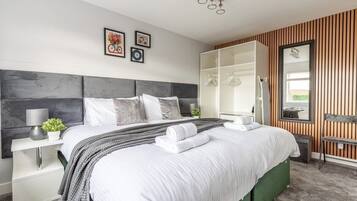 Een moderne slaapkamer met een groot bed, een garderobe, een spiegel en een nachtkastje.
