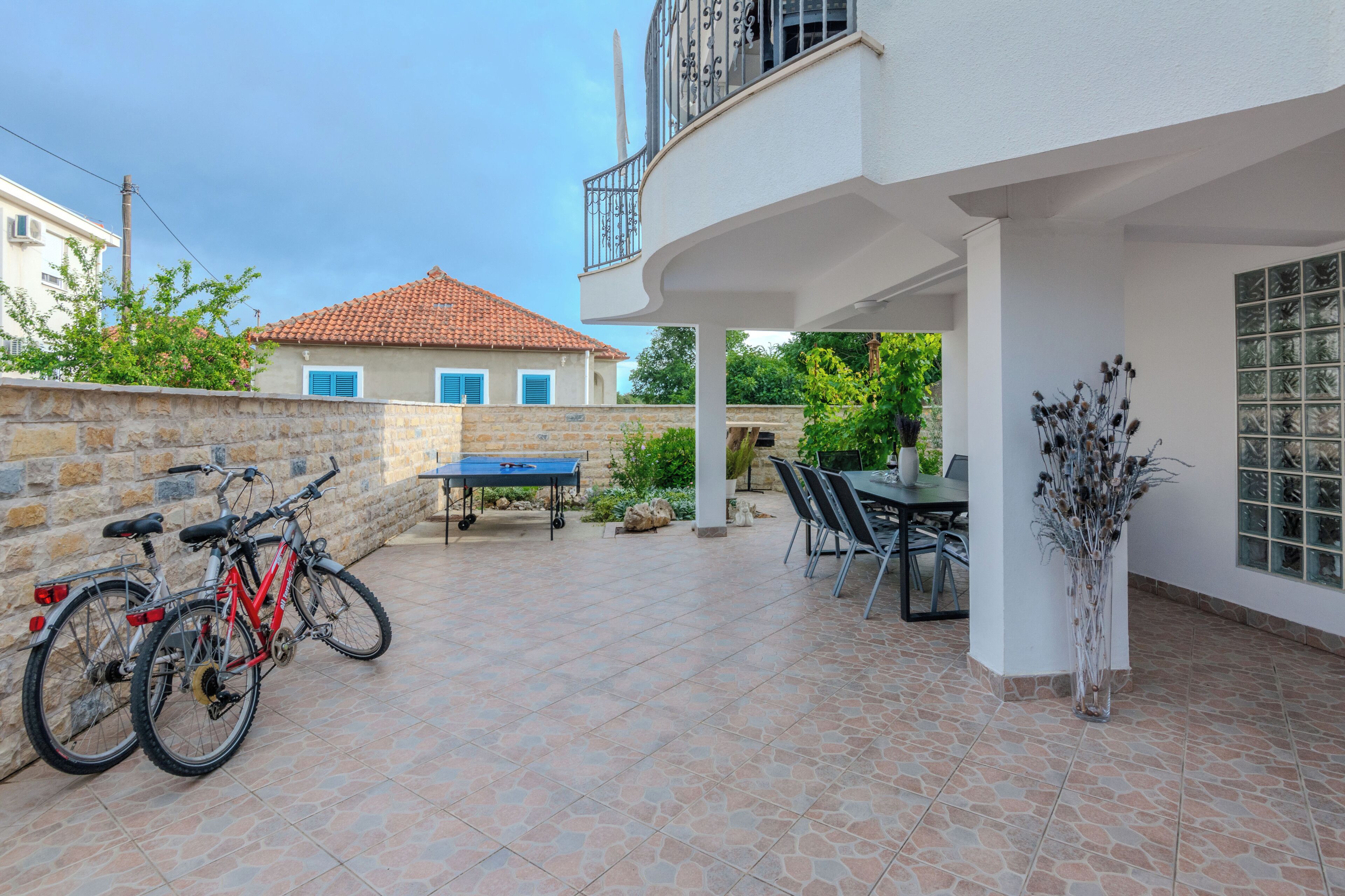 A patio area with a table and chairs, a potted plant, and bicycles.