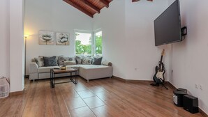A living room with a sofa, a coffee table, a guitar, and a TV mounted on the wall. - Holiday home Lucic (Nin)