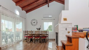 A spacious dining area with a wooden table and chairs, a clock on the wall, and a fireplace. - Holiday home Lucic (Nin)