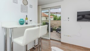 A modern kitchen with a white countertop, two white bar stools, a teal vase, and a wine bottle. - Holiday home Lucic (Nin)