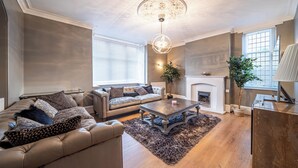 Ein Wohnzimmer mit einer Couch, einem Couchtisch, einem Kamin und einer Deckenleuchte.