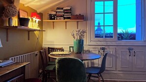 Un comedor acogedor con una mesa redonda, sillas y una ventana que ofrece vistas a un edificio.
