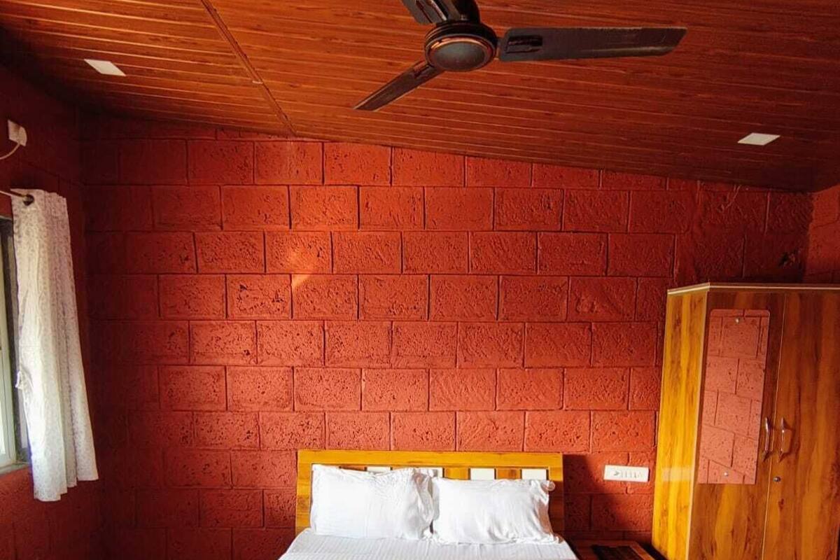 A room with a wooden ceiling, a bed with white linens, and a brick wall.