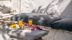 A stone bench with cushions, two glasses of orange juice, and lemons on a stone ledge. - Serene Retreat- Sleeps 4, Wifi, Courtyard (Lefkada)