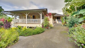 Ein zweistöckiges Haus mit Veranda, umgeben von üppiger tropischer Vegetation.