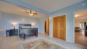 Ein Schlafzimmer mit einem Bett, Nachttischen, einem Deckenventilator und einer Holztür.