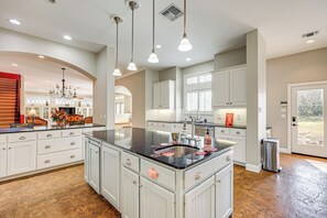 A spacious kitchen with a large island, white cabinetry, and pendant lighting.