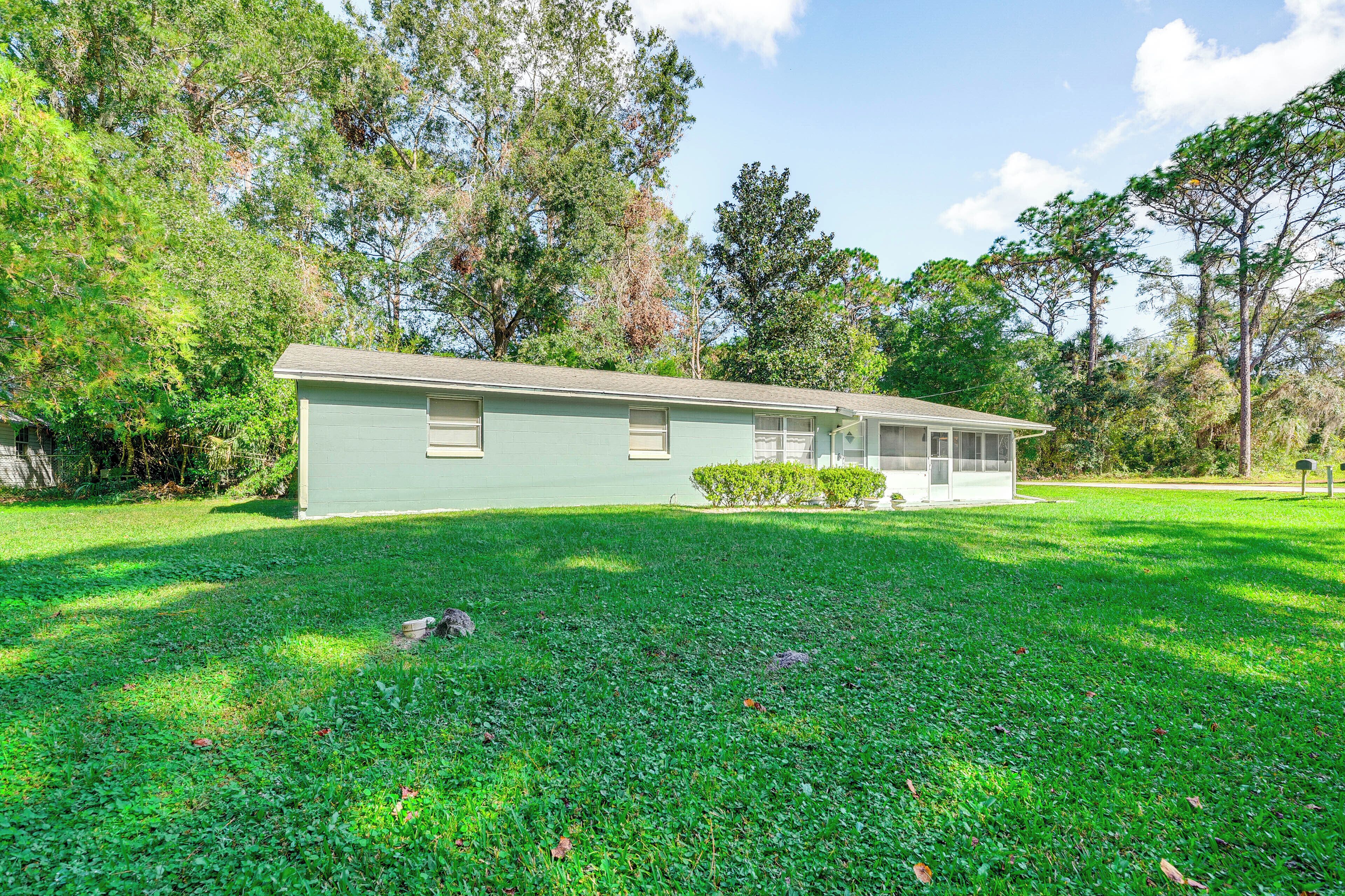 A single-story house with a front porch, surrounded by a well-maintained lawn and trees.